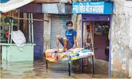  ?? — PTI ?? A man sits on an elevated stand after floods due to heavy rain in Fatehpur. Several parts of Rajasthan recorded rainfall Wednesday due to an active western disturbanc­e, keeping the mercury below the 40 Celsius-mark in most regions of the state.