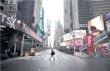  ??  ?? GHOST TOWN: A tourist crosses 7th Avenue in Times Square on Friday in New York City.