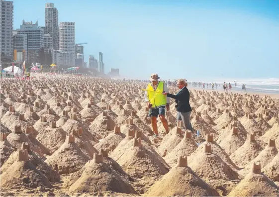  ?? Picture: GLENN HAMPSON ?? Guinnes World Records judge Solvej Malouf and assistant Phil Bennett run their eye over more than 3000 castles built at Surfers Paradise.