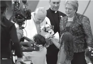  ??  ?? FLOWERS FROM CHILE Pope Francis (C-L) is given flowers by children as he is welcomed to the Arturo Merino Benitez airport by Chilean President Michelle Bachelet (R) in Santiago Monday.