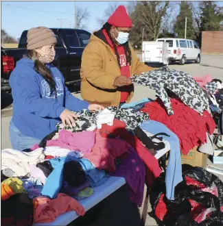  ?? Katie West • Times-Herald ?? Ashley Boone, left, and Kittrel Wynne fold clothes for St. Francis County residents to pick up for free. A group of Good Samaritans organized the free clothes giveaway held Saturday at the Grant Street parking lot.