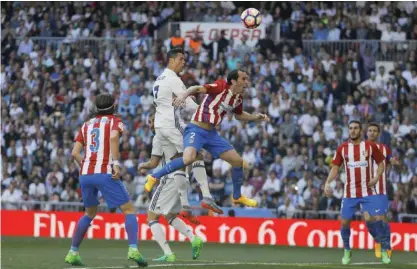  ??  ?? MADRID: Real Madrid’s Cristiano Ronaldo, top left, goes for a header with Atletico Madrid’s Diego Godin, top right, during the La Liga soccer match between Real Madrid and Atletico Madrid at the Santiago Bernabeu stadium in Madrid, yesterday. — AP