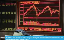  ??  ?? BEIJING: A man rests as he keeps an eye on stock price movements displayed on a screen at a securities company in Beijing. — AFP