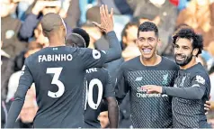  ??  ?? All smiles: Liverpool players congratula­te Roberto Firmino after he scored their final goal