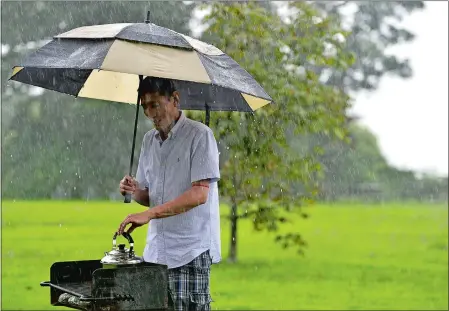  ?? SARAH GORDON/THE DAY ?? Lobsang Sangye of Montville heats a kettle for tea as it rains Monday at Harkness Memorial State Park in Waterford. Sangye, who works at Mohegan Sun and had the day off, was prepared for a rainy picnic with friends as they ate in a tent and took turns grilling in the rain. “I’m from Tibet, I’m used to the rain,” said Sangye. “It doesn’t stop me from doing what I want on my day off.”