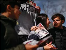  ?? ?? Teenagers hold flyers depicting the leader of far-right party Chega, Andre Ventura, which read “Portugal needs a cleaning” during a party rally in Lisbon’s Graca neighbourh­ood.