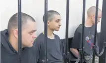  ?? Photo / AP ?? Two British citizens Aiden Aslin, left, and Shaun Pinner, right, and Moroccan Saaudun Brahim, centre, sit behind bars in a courtroom in Donetsk. The trio have been sentenced to death by pro-Moscow rebels.