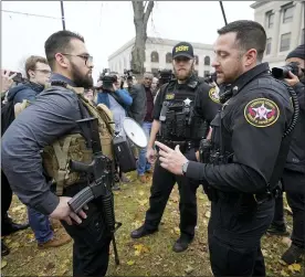  ?? AP PHOTO/PAUL SANCYA ?? Kenosha County Sheriffs Department officers question a protester carrying a rifle outside the Kenosha County Courthouse on Wednesday in Kenosha, Wis., during the Kyle Rittenhous­e murder trial.