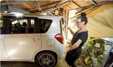  ??  ?? Ewington checks her car after winds knocked over the tree at her New Plymouth home.