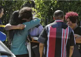  ?? Mark Ralston / AFP / Getty Images ?? People comfort one another at the scene where three were killed and 12 others injured on Saturday during a shooting after a dispute at a pop-up Jamaican restaurant in Los Angeles.