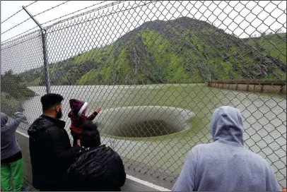  ?? The Associated Press ?? GLORY HOLE: People stop to watch water flow into the iconic Glory Hole spillway at the Monticello Dam on Monday in Lake Berryessa, Calif. Water is flowing for the first time in over a decade into the 72-foot diameter hole due to the recent storms in...