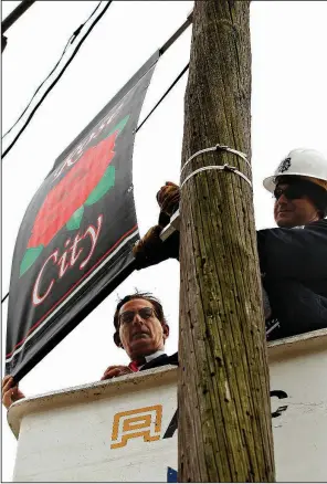  ?? Arkansas Democrat-Gazette/THOMAS METTHE ?? James Bartlett (right), with North Little Rock Electric, helps Danny Bradley, chief of staff for the North Little Rock mayor’s office, put up the first Rose City banner on a light pole Thursday outside the Rose City Shopping Center in North Little Rock.