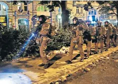  ??  ?? Heavily armed special police forces walk through the Schanzenvi­ertel area of Hamburg