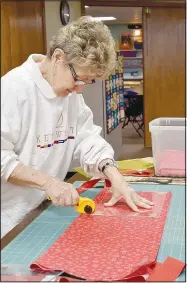  ?? (NWA Democrat-Gazette/Rachel Dickerson) ?? Margo Webb cuts fabric into blocks for quilts.