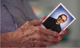  ?? Photograph: Marvin Recinos/AFP/Getty ?? Gaspar Romero holds a holy card portraying his brother, the late Monsignor Oscar ArnulfoRom­ero.