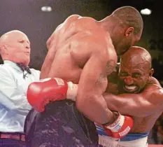  ?? Foto: Jeff Haynes, dpa ?? Ringrichte­r Lane Mills geht dazwischen – doch Mike Tyson hatte bereits das Ohr von Evander Holyfield erwischt.