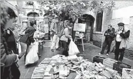  ?? LUCA BRUNO/AP ?? Volunteers pile damaged books outside renowned bookstore Acqua Alta, or High Water, on Saturday in Venice, Italy. The flood soaked “thousands and thousands” of books.