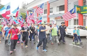  ??  ?? PAIRIN dan Thomas mengetuai perarakan Hari Kebangsaan mengelilin­g Pekan Tambunan dengan mengibarka­n Jalur Gemilang dan bendera Sabah.