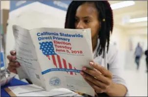  ?? The Associated Press ?? CALIFORNIA PRIMARY: Nikko Johnson reviews the California Primary election guide on Tuesday at San Francisco City Hall. The 40-year-old nurse was waiting for her mother to arrive at the polling station so they could vote together.