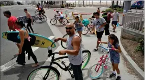  ?? AP PHOTO/MARCIO JOSE SANCHEZ ?? People wait to cross Pacific Coast Highway Sunday, April 26, 2020, in Huntington Beach, Calif. A lingering heat wave lured people to California beaches, rivers and trails again, prompting warnings from officials that defiance of stay-athome orders could reverse progress and bring the coronaviru­s surging back.