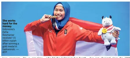  ??  ?? She works hard for the money: Indonesia’s Defia Rosmaniar received 1.5 billion rupiah after winning a gold medal in taekwondo. — AFP