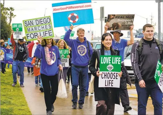 ?? NELVIN C. CEPEDA U-T PHOTOS ?? Abortion opponents march around the County Administra­tion Center on Saturday during the 10th Annual San Diego Walk for Life. A rally preceded the walk, where speakers encouraged pressing lawmakers to restrict abortion access.