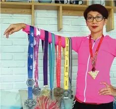  ?? BAGUS PUTRA PAMUNGKAS/JAWA POS ?? HASIL KERINGAT: Patricia Heny menunjukka­n sebagian medali yang didapatnya dari sejumlah race yang dia ikuti. Total sudah 40 race yang dia ikuti selama enam tahun.