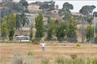  ?? Photos by Paul Chinn / The Chronicle ?? A man stretches in a parcel of land at India Basin in San Francisco, where a developer is seeking approval to build 1,575 units of housing and 150,000 square feet of commercial space.