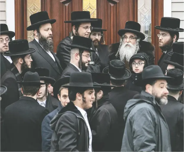  ?? Jeenah Moon / REUTERS ?? Rabbi Chaim Rottenberg and others gather outside his home in Monsey, N.Y., where an attacker burst in Saturday evening and stabbed five people.