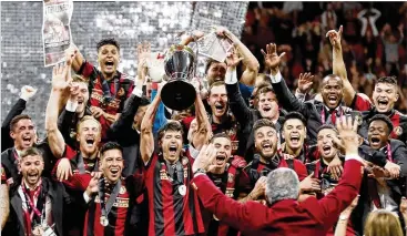  ?? BOB ANDRES / BANDRES@AJC.COM ?? Atlanta United players celebrate with owner Arthur Blank after winning the 2018 MLS Cup.