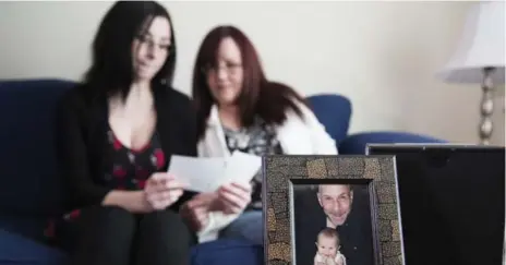  ?? ANNE-MARIE JACKSON PHOTOS/TORONTO STAR ?? Lynda Meadus-Graham, right, with her daughter Courtney Graham, look through photos of Lynda’s husband and Courtney’s father.