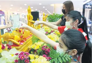  ?? SOMCHAI POOMLARD ?? Girls bathe Buddha statues with lustral water in a traditiona­l practice associated with the Songkran festival at Seacon Square shopping centre.