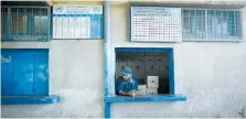  ?? (Mohammed Salem/Reuters) ?? AN EMPLOYEE looks out of a window of a store at an UNRWA food distributi­on center in Gaza.