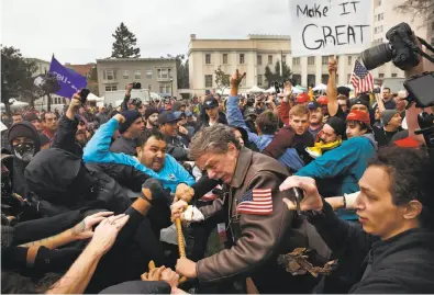  ?? Leah Millis / The Chronicle ?? BERKELEY, MARCH 17: Tom Condon of San Francisco (center), a Trump supporter, becomes entangled in a fight during a pro-Trump rally and march at Martin Luther King Jr. Civic Center Park.