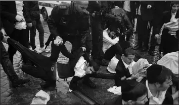  ?? LEO CORREA / ASSOCIATED PRESS ?? Israeli police officers scuffle with ultra-orthodox Jewish men Monday in Jerusalem during a protest against a potential new draft law that could end their exemptions from military service.