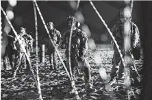  ?? Marco Ugarte / Associated Press ?? U.S. Border Patrol agents stand on the U.S. side of the border, peering through the concertina wire where the border meets the Pacific Ocean.