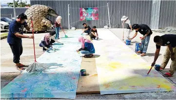  ??  ?? UCSF artists working on another impression­ism piece using unconventi­onal tools such as broom, mop, wooden sticks and dish sponges.