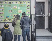  ?? LIAM RICHARDS THE CANADIAN PRESS ?? People look at a memorial wall for the Humboldt Broncos during a game between the Estevan Bruins and Nipawin Hawks in Nipawin, on April 14.