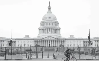  ?? PATRICK SEMANSKY/AP ?? A bicyclist rides past security fencing set up surroundin­g the U.S. Capitol in Washington on Friday, in response to the storming of the Capitol two days earlier by supporters of President Donald Trump.