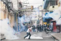  ??  ?? RIÑEN. Un manifestan­te hace frente a granaderos durante la manifestac­ión contra el Gobierno, en el Centro de Tegucigalp­a.