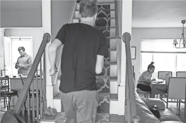  ?? PHOTOS BY ANTRANIK TAVITIAN/DFP ?? Bob Carleton checks historical facts for his son, Andrew, while Danielle Vernon-Carleton, right, tutors virtually and Connor Carleton, center, runs up the stairs.