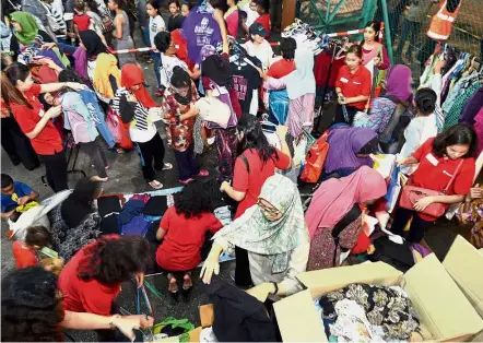 ??  ?? Helping hand: The homeless and urban poor browsing through the clothes at Kedai Jalanan, assisted by Yayasan Gamuda volunteers.