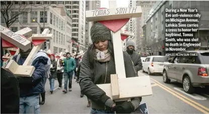  ?? ASHLEE REZIN/ SUN- TIMES ?? During a New Year’s Eve anti- violence rally on Michigan Avenue, Latekia Sims carries a cross to honor her boyfriend, Tomas Smith, who was shot to death in Englewood in November.