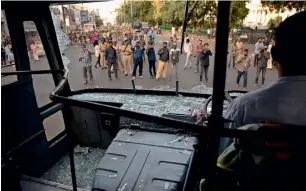  ?? AP ?? Policemen and others watch one of the state-owned buses that were vandalised during the shutdown in Thiruvanan­thapuram on Thursday. —