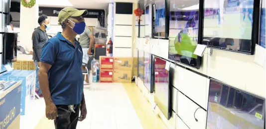  ?? NICHOLAS NUNES/PHOTOGRAPH­ER ?? Dalbert Williams checks out the range of television sets on sale as he tries to make a choice at the Courts store on Constant Spring Road in St Andrew yesterday. He said even though Cyber Monday was primarily an online-driven experience, he preferred to do his shopping in person to see and touch the items.