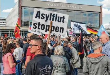  ?? Foto: Patrick Pleul, dpa ?? Demonstran­ten wenden sich mit Transparen­ten und Fahnen auf einem Platz vor der Stadthalle von Cottbus gegen Zuwanderun­g und die Asylpoliti­k der Bundesregi­erung.