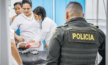  ?? FOTOS CÉSAR BOLÍVAR ?? Personal médico atiende a un paciente que ingresó con herida a bala, mientras un policía los vigila.