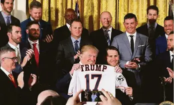  ?? Chip Somodevill­a / Getty Images ?? Surrounded by teammates and coaches, Josh Reddick helps President Donald Trump display his honorary Astros jersey during the World Series champions’ visit to the White House on Monday.