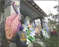  ??  ?? Parade float workers Travis Keene (left) and Joey Mercer position a pelican while fellow crew member Chelsea Kamm (right) looks on while decorating a house.