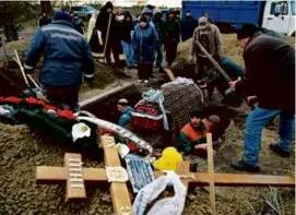  ?? GENYA SAVILOV/AFP/GETTY IMAGES ?? Workers buried the coffin of a woman killed in an airstrike during a funeral ceremony in the Kharkiv region on Monday.